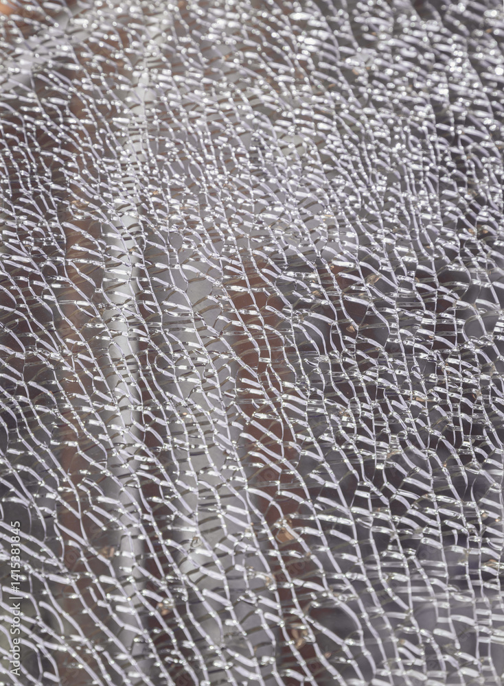Detail of broken tempered glass pane too many small irregular shape pieces holding together. Texture of cracked broken glass cracked by impact, Cracks on the glass surface background, Space for text.