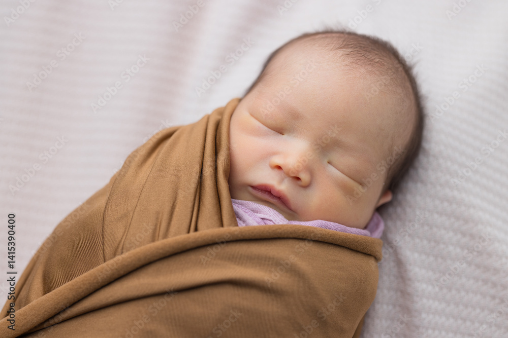 Sleeping newborn wrapped in warm brown blanket