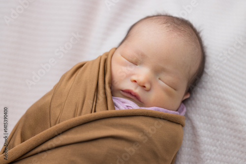 Sleeping newborn wrapped in warm brown blanket