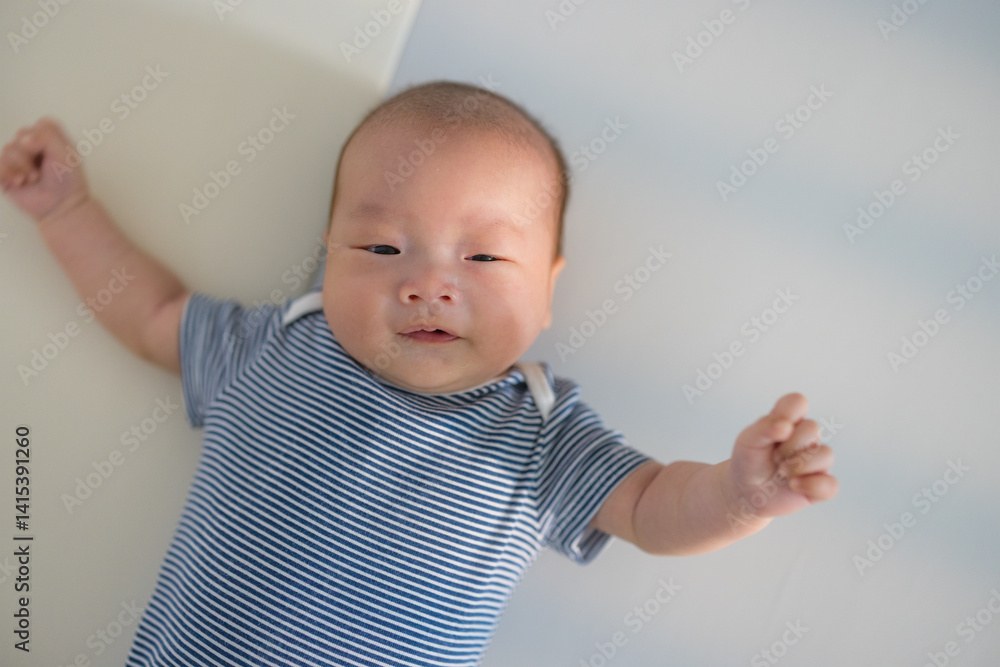 Newborn baby with blue outfit lying on bed