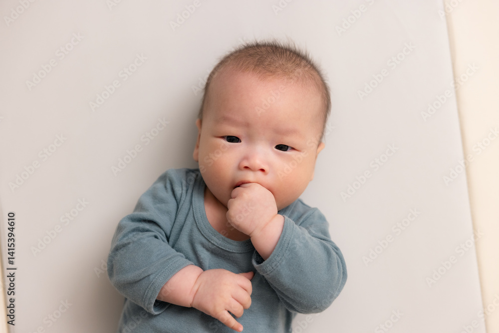Adorable baby sucking hand in soft outfit