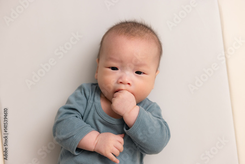Adorable baby sucking hand in soft outfit