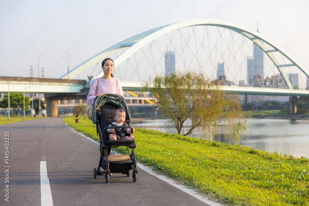 Mum walking with baby on stroller at river park