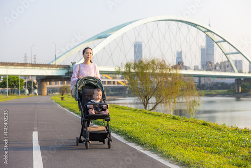 Obraz na płótnie Mum walking with baby on stroller at river park w salonie