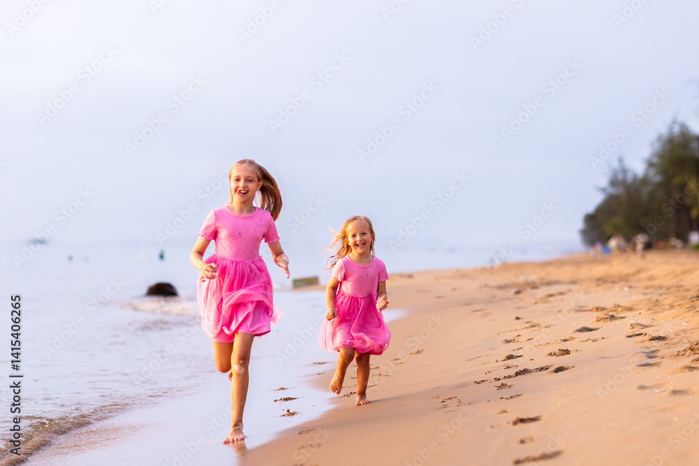 Two adorable caucasian little girls walking on sandy beach at hot summer day. Sisters having fun during tropical vacation on sea Two adorable caucasian little girls walking on sandy beach at hot summer day. Sisters having fun during tropical vacation on sea