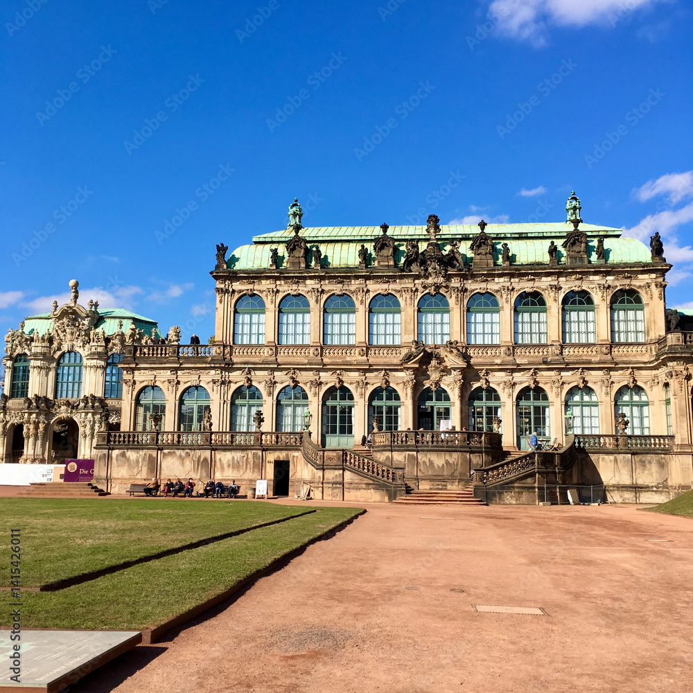 Obraz premium The Zwinger Palace, a magnificent baroque masterpiece in Dresden, Germany, showcases its intricate design and stunning architecture under the clear blue sky.