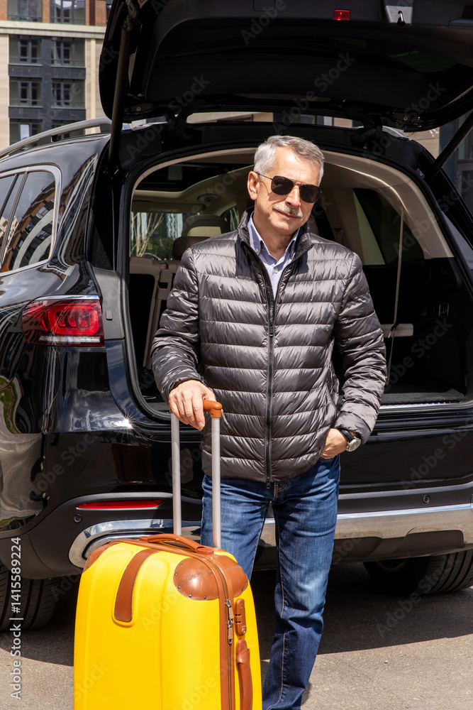 Man standing in back of car smiling and getting ready to go. Senior man standing near open trunk of a car. road trip