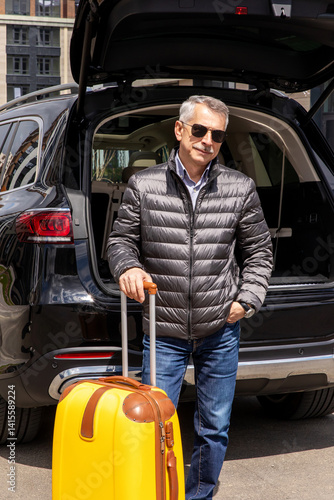 Obraz na płótnie Man standing in back of car smiling and getting ready to go. Senior man standing near open trunk of a car. road trip w salonie