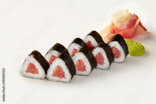 Triangular sushi pieces with tuna filling, wasabi, and ginger on white background