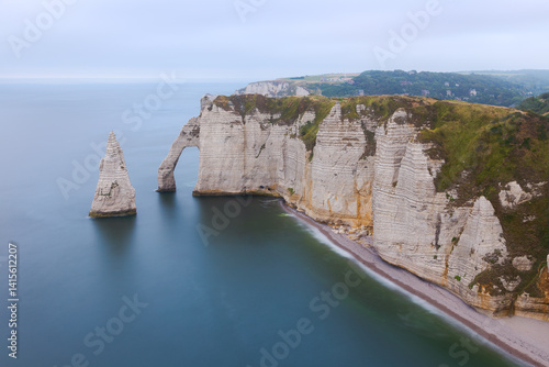 White chalk cliffs and natural arch of Étretat on the Normandy coast under soft light and calm sea