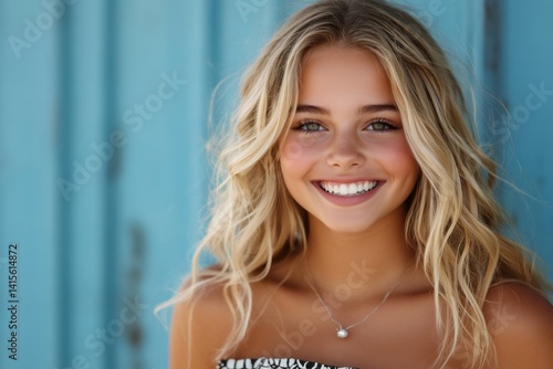 Blonde teenager smiling with blue background