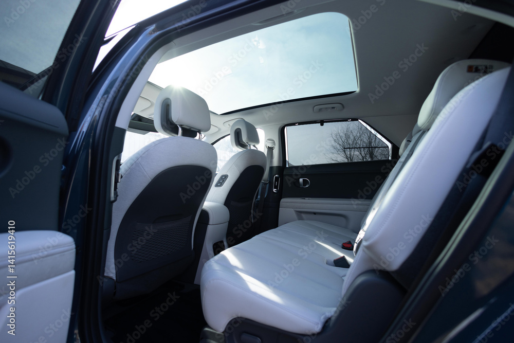Fototapeta premium Panoramic glass sun roof in the modern electric car. Clean sunroof and view at the sky from the inside or car interior. The view from the empty car with rear seats