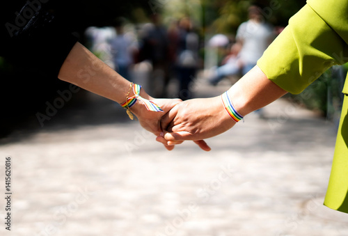 Schilderij op canvas Couple holding hands showing rainbow bracelets: celebrating lgbtq+ pride and lov