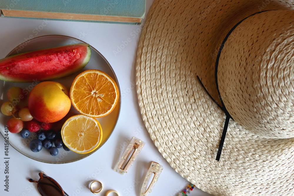 Glass of cocktail, straw hat, sunglasses, books, fresh fruit, chocolate and accessories. Summer essentials on the table. Top view.