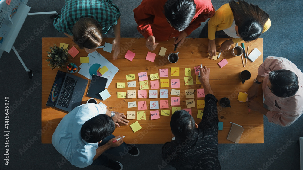 Top view of smart diverse business team working together and clapping hand while brainstorming marketing idea or creative startup project by using sticky notes and stick at meeting table. Convocation.