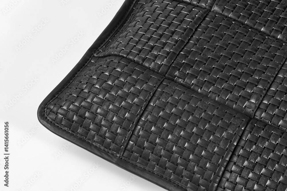 Corner of black leather woven placemat showing intricate detailing
