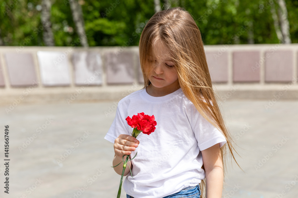 Victory Day. Little Girl with red carnations at the Eternal flame near the monument of Unknown soldiers tomb. Patriotic education at school.
