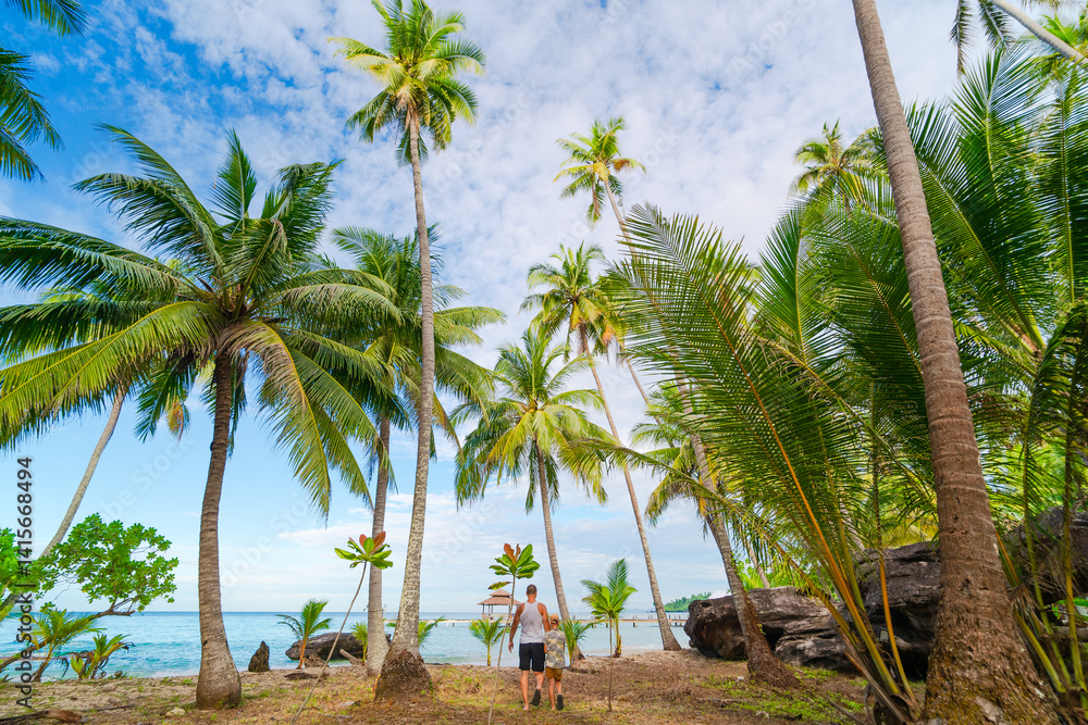 Obraz premium Father and son walking on tropical seaside 