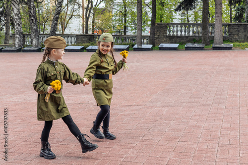 Obraz na płótnie Patriotic education of youth. Little girls in an old Soviet military uniform laying flowers at the eternal flame near the monument to fallen soldiers in world War II. Victory Day on May 9. Copy space w salonie