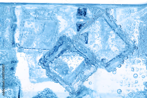 Refreshing soda water with ice cubes as background, closeup