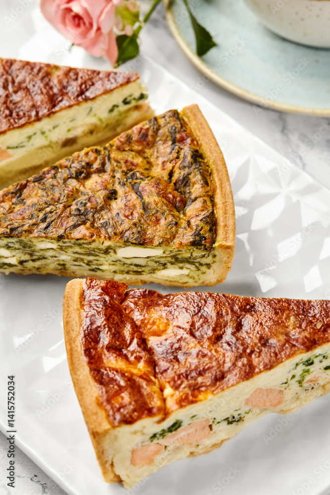 Delicious homemade quiches with salmon, spinach and mushrooms filling resting on white plate