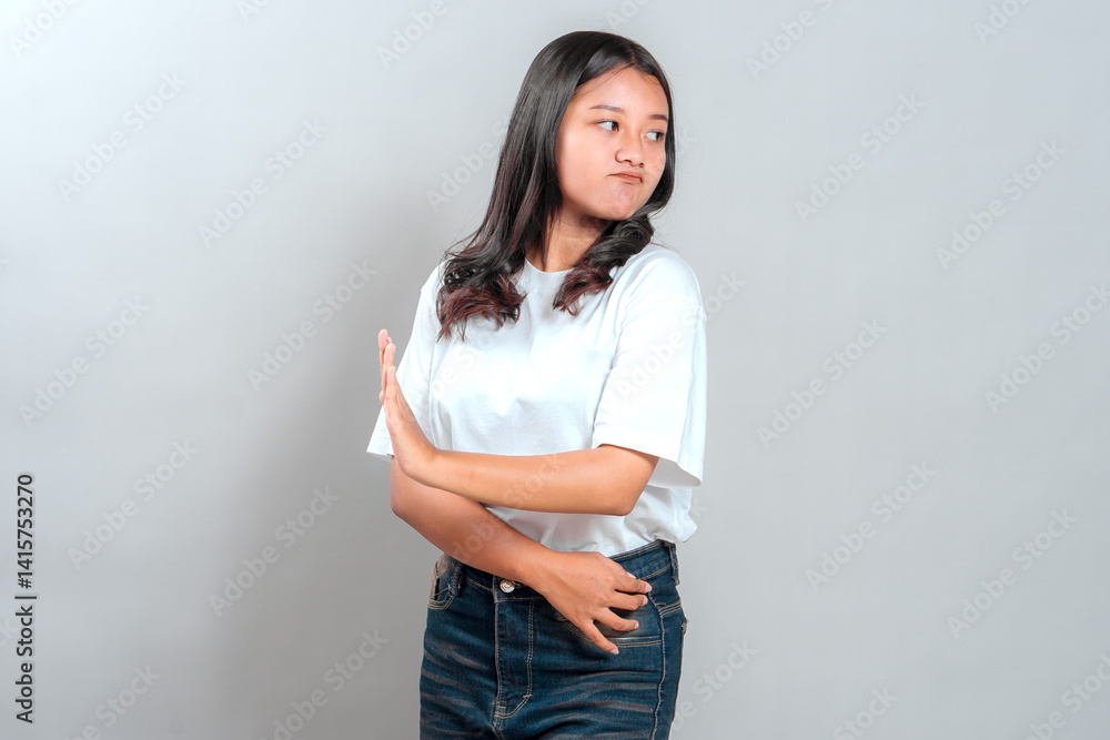 Portrait of a serious young Asian woman with a stern facial expression, holding her hand forward in a stop gesture, expressing refusal, warning, or disagreement against a plain background. Portrait of a serious young Asian woman with a stern facial expression, holding her hand forward in a stop gesture, expressing refusal, warning, or disagreement against a plain background.