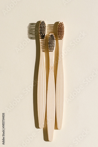 Eco friendly Bamboo toothbrushes with white bristles at sunlight with dark shadows on beige background. Sustainable living concepts, minimal style aesthetic photo, top view set wooden brushes