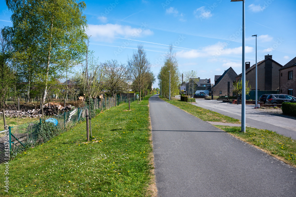 Obraz premium Cycling route along backyards at old train route L 85 in Kluisbergen, East Flemish Region, Belgium