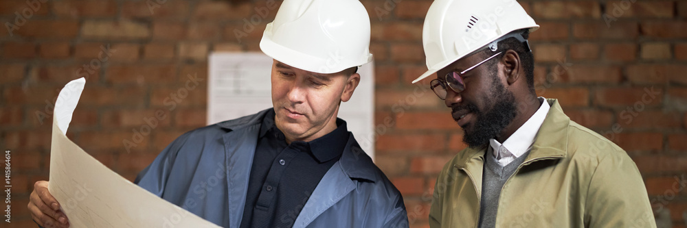 Website banner with two highly qualified biracial construction workers looking at layout plan Website banner with two highly qualified biracial construction workers looking at layout plan