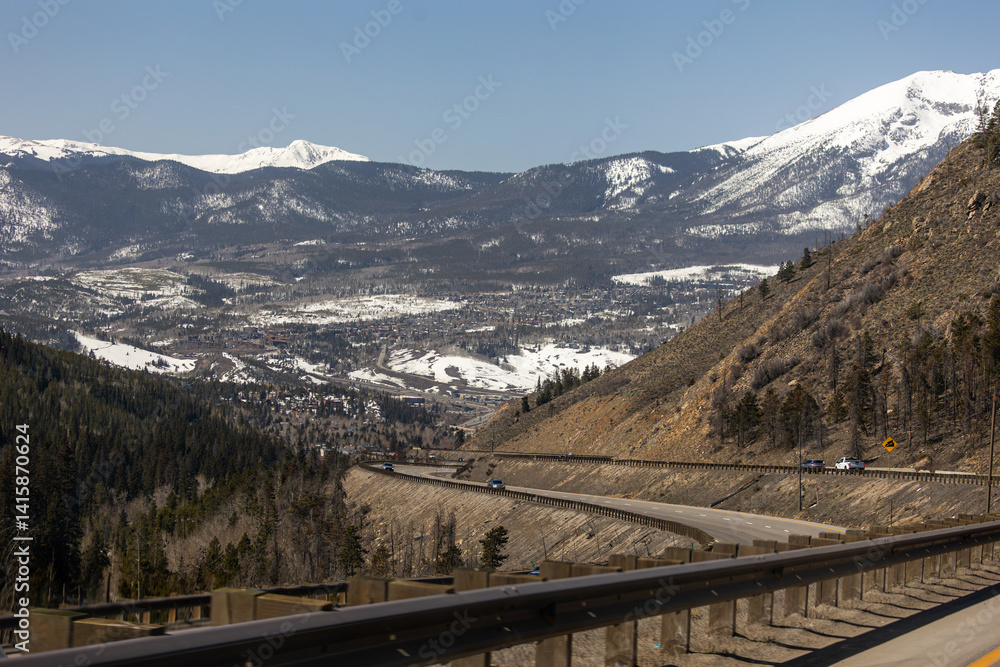 Fototapeta premium Scenic drive on I-70 in Colorado with stunning views of the snow-covered Rocky Mountains under clear blue skies, perfect for a winter road trip