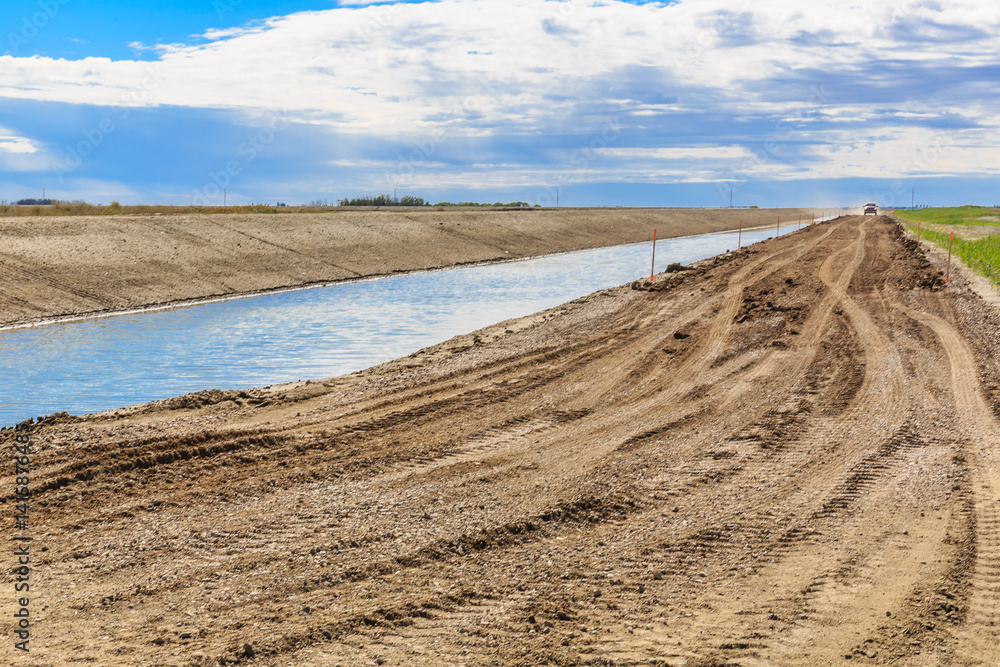 Dirt road with a river running alongside it Dirt road with a river running alongside it