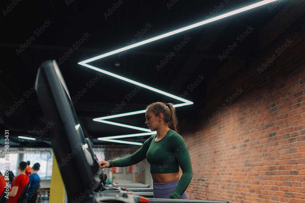Young woman setting up treadmill for cardio workout in modern gym Young woman setting up treadmill for cardio workout in modern gym