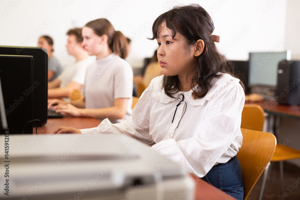 Portrait of diligent asian college girl studying in university computer room using computer