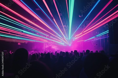 Vibrant laser lights illuminate a large crowd at a concert, creating an electric atmosphere.