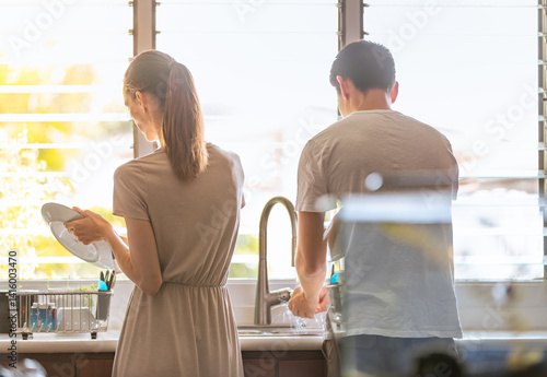 Fotografie Couple washing the dishes together doing home chores housework, family togethern