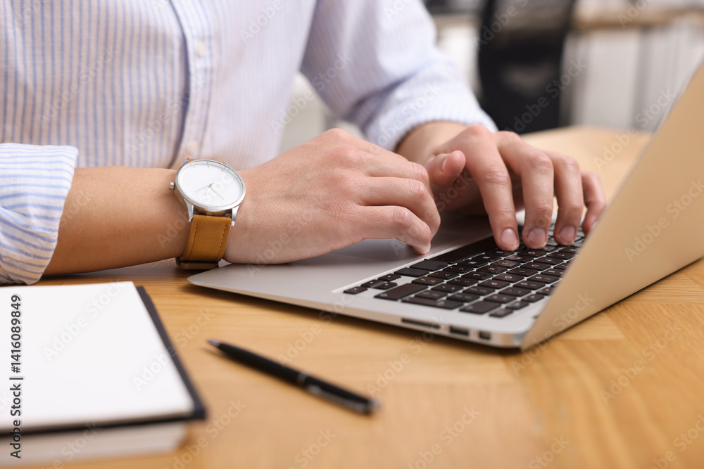 Man working on laptop at wooden desk in office, closeup Man working on laptop at wooden desk in office, closeup