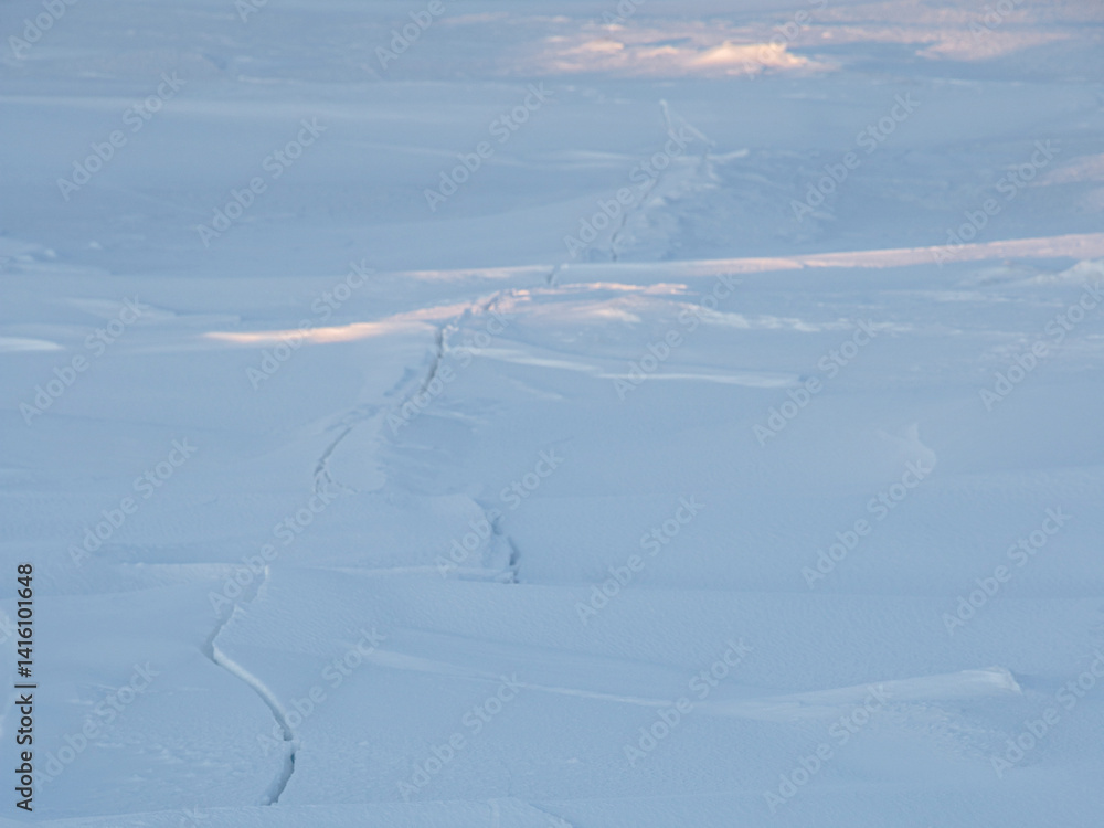 Crack in the ice cover. Snow covered ice. Cracked ice floes on the sea in the Arctic. Polar region.