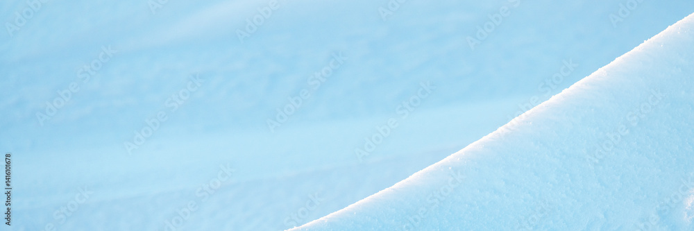 Wide panoramic winter background with snowy ground. Natural snow texture. Wind sculpted patterns on snow surface. Closeup top view with copy space.