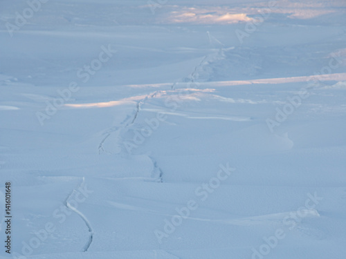 Crack in the ice cover. Snow covered ice. Cracked ice floes on the sea in the Arctic. Polar region.