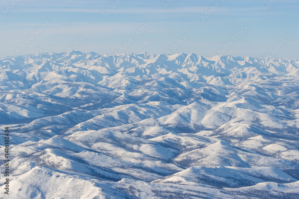 Aerial view of snow-capped mountains. Winter snowy mountain landscape. Air travel to the far North of Russia. Kolyma Mountains, Magadan Region, Siberia, Russian Far East. Great for the background.
