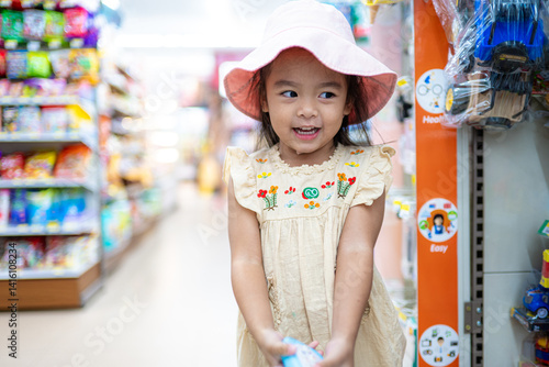 Obraz na płótnie Little girl enjoy shopping toy on shelf in supermarket w salonie