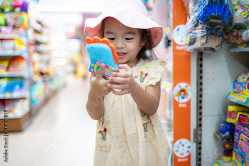 Little girl enjoy shopping toy on shelf in supermarket