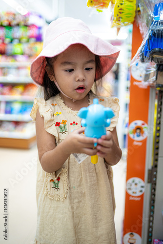 Little girl enjoy shopping toy on shelf in supermarket