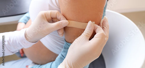 Young pregnant woman receiving medical patch after vaccination at hospital, c...