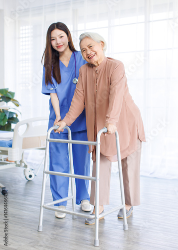 Obraz na płótnie Asian doctor or caregiver helping assistance old woman to standing with walker in hospital, Young nurse supporting senior patient walk slowly frame nursing home care, Healthy wellness being concept. w salonie