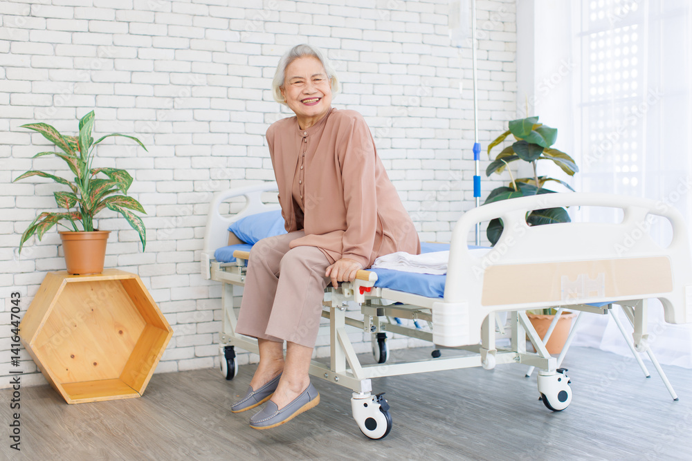 Asian senior woman smiling, happy old patient with grey hair in brown dress thumb up while sitting on bed in hospital, Healthcare elderly rehabilitation supporting care therapy center wellness being.