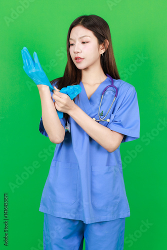 Obraz na płótnie Portrait of asian young woman confident beautiful, smiling nurse in blue uniform standing looking at camera pose on green background, Consultation caregiver healthcare medical assistant professional. w salonie