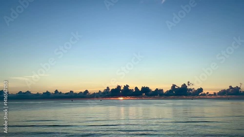 Timelapse sunrise beach. Sun rising behind dark clouds and sea wave in the morning.