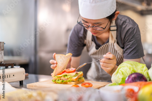 Smiling Young Female Chef Preparing a Sandwich in a Professional Kitchen