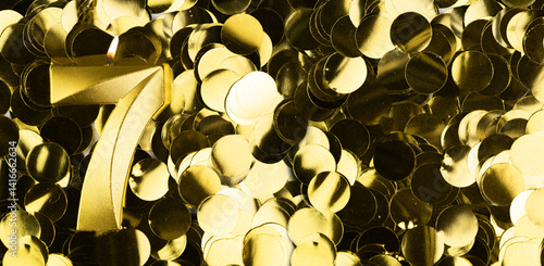 Photos Golden number seven candle on shiny yellow confetti background